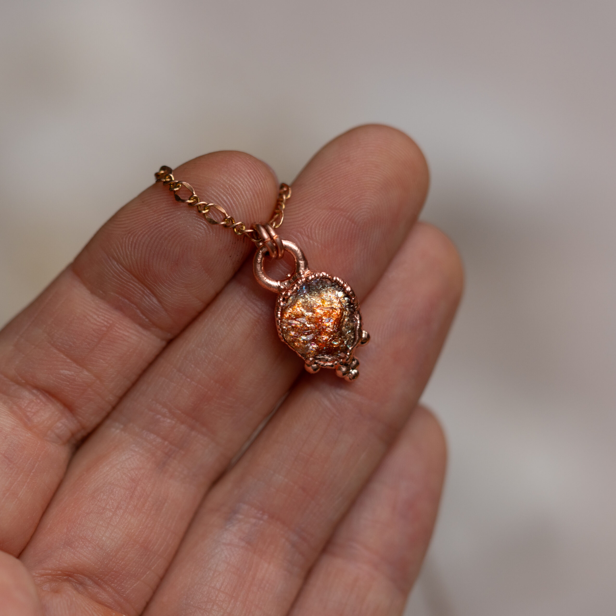 naszyjnik z surowym kamieniem słonecznym na dłoni