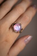Ein Ring mit einem rosa Mondstein an der Hand.